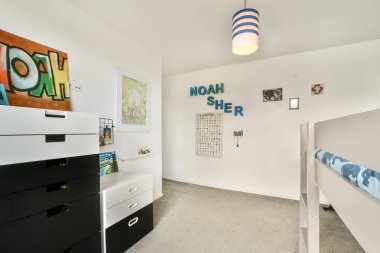 İçinde eğlenceli dekorasyonlar, canlı renkler ve organize depolama bulunan modern bir çocuk odası. Kişisel dokunuşları olan küçük bir çocuk için ideal..