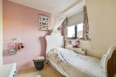 Güzel dekore edilmiş yumuşak pastel renkler, çiçek perdeleri ve kelebek sanatı sergilenen bir yatak odası sıcak ve davetkar bir atmosfer yaratıyor..