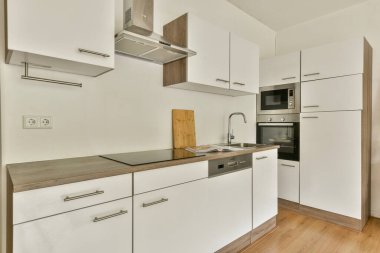 Zarif beyaz dolaplar, şık ahşap tezgah ve zarif bir mutfak deneyimi için çağdaş aletler içeren geniş, modern bir mutfak..