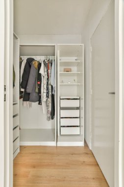 Şık, modern bir gardırop, iç mekanların minimalist estetiklerle işlevselliğini artıran organize giysiler ve raflar sergiliyor..