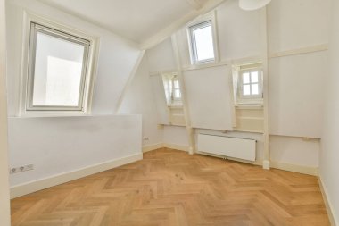 Parlak, havadar bir oda, şık üçgen pencereler ve sıcak ahşap bir zemin, rahatlama ya da çalışma için ideal. Minimalist tasarım geniş hissi arttırır..