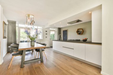 Çağdaş bir mutfak, gösterişli bir dolap, şık bir ışıklandırma, ve çiçeklerle süslenmiş rahat bir yemek alanı, atmosferi davet eden odalar..