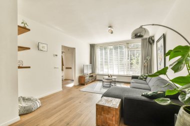 Parlak ve ferah oturma odasında şık mobilyalar, büyük pencereler ve rahat bir ortam, rahatlama ve sosyal toplantılar için mükemmel..