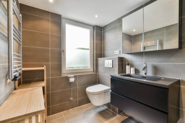 Pürüzsüz ve modern bir banyo koyu fayanslı minimalist bir estetik, çağdaş bir kibir ve büyük bir pencereden gelen doğal ışık..