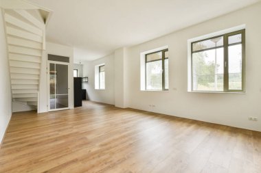 Parlak, minimalist iç mekan, ahşap döşeme ve çağdaş merdiven tasarımının yer aldığı geniş pencerelerden akan doğal ışığı sergiliyor..