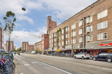 Canlı bir sokak gösterisi park halindeki bisikletler, büyüleyici mimari ve yayalar parçalı bulutlu bir gökyüzü altında, şehir yaşamını somutlaştırıyor..