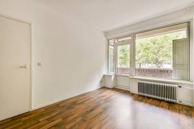 Geniş bir pencereye sahip minimalist bir iç mekan doğal ışığın odayı su basmasına izin veriyor. Ahşap zemin uzaya sıcaklık katarak davetkar atmosferini arttırır..