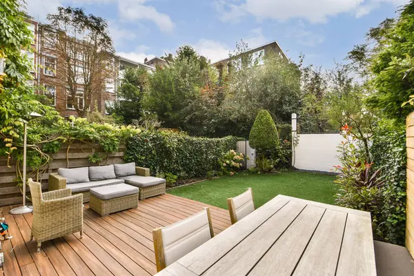 Güzel tasarlanmış, yeşil çimenli, şık bir açık hava koltuğu ve sakin bir geri çekilme yaratan yemyeşil bitkileri olan modern bir bahçe..