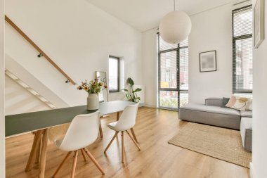 Parlak ve havadar minimalist oturma odası gösterişli bir yemek masası, rahat bir kanepe ve çağdaş bir ortamda şık dekorlar..