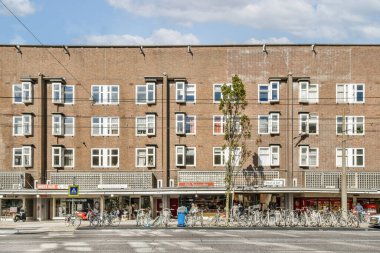 Şehir merkezinde bisiklet ve yayalarla çevrili sayısız pencerenin yer aldığı çarpıcı bir modern bina cephesi. İşlevsellik ve tasarımın bir karışımı.