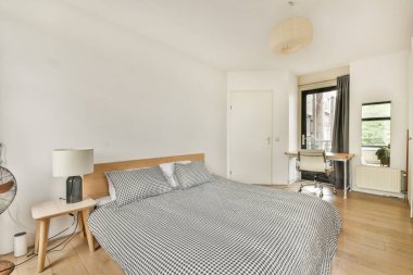 İçinde kareli yatak odaları, minimalist mobilyalar ve büyük pencerelerden içeri akan doğal ışık bulunan çağdaş bir yatak odası..