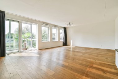 Parlak ve havadar bir oda, ahşap döşeme, büyük pencereler ve en az dekorasyonla, sakin ve davetkar bir atmosfer yaratarak rahatlamak için ideal..