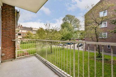 Çağdaş bir apartman balkonundan sakin bir manzara, yemyeşil manzaralı, kentsel bir ortamın ortasında ferahlatıcı bir açık alan sağlıyor..