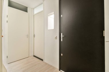 Parlak siyah kapısı ve parlak ahşap döşemesi olan minimalist dizaynlı çağdaş bir iç mekan girişi davetkar bir atmosfer yaratıyor..