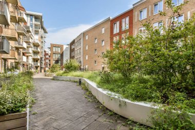 Huzurlu bir yol, verimli yeşillikle bezenmiş çağdaş konut binalarının arasından geçer. Doğayı harmanlayan ve modern yaşamı uyumlu kılar..