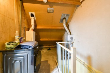 Çamaşır makinesi, kurutma makinesi ve çeşitli depolama malzemelerinin olduğu rahat bir çamaşır odası. Ev işleri için tasarlanmış işlevsel ve pratik bir alan..