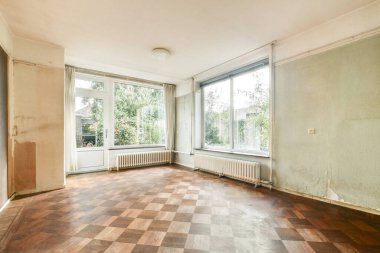 Basit ve ferah bir iç tasarım sergileyen, bol doğal ışık alan geniş pencereli boş bir oda..