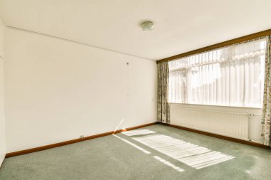 Geniş ve minimalist iç mekan. Perdelerin arasından süzülen doğal ışıkla basit ama zarif bir tasarımı ön plana çıkarıyor..