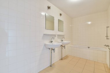 Temiz çizgiler, beyaz fayanslar, çift lavabo ve küvet içeren çağdaş bir banyo, minimalist ve ferah bir atmosfer yaratıyor..
