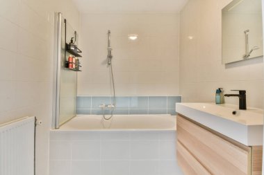 Temiz, modern bir banyo. Duş ve küvet kombinasyonu. Şık ahşap dolaplar ve modern kapaklar..