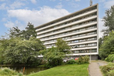 Şık, modern bir konut binası yemyeşil bir bölgenin ve sakin bir suyun yanında zarif bir şekilde duruyor. Doğal ortamlarda çağdaş mimariyi göstermek için ideal.