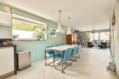 Parlak bir tasarımı, ahşap döşemeleri ve şık mobilyaları olan modern bir minimalist mutfak ve yemek alanı aile toplantıları için davetiye alanı oluşturuyor..