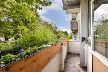 Bereketli yeşilliklerle çevrili canlı çiçek ekicilerin bulunduğu sakin bir balkon manzarası. Rahatlamak ve doğanın tadını çıkarmak için mükemmel..