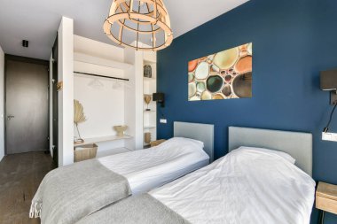 Çağdaş bir yatak odası, ikiz yataklar, şık bir dekor ve güzel bir duvar sanat eseri. Oda modern estetik ile rahatlığı harmanlıyor..