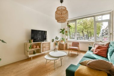 Rahat bir kanepesi, televizyonu ve geniş pencereleri olan şık bir oturma odası. Bol miktarda doğal ışık alıyor ve davetkar bir atmosfer yaratıyor..