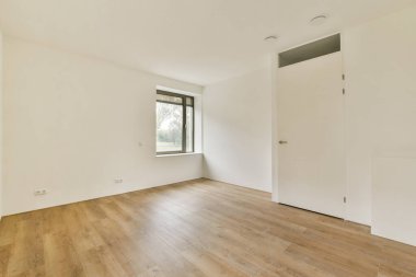 Ahşap döşemeli, geniş pencereli, minimalist dekorlu ve doğal ışığa odaklı geniş ve modern bir iç mekan..