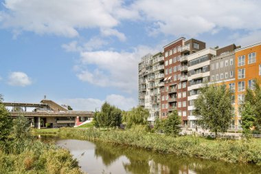 Çağdaş binalar, bereketli yeşilliklerle çevrili ve doğa ile kentsel mimarinin bir karışımını sergileyen sakin bir su yolu hizasında..