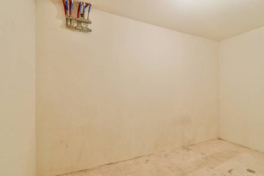 Çıplak duvarları ve bitmemiş zemini olan boş beyaz bir oda, minimalist estetiği ve çeşitli kullanım potansiyelini temsil ediyor..