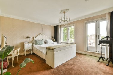 Geniş bir yatak odası lüks bir yatak odası, pencerelerden gelen doğal ışık ve şık dekorasyon unsurları. Konfor ve güzelliğin karışımı huzurlu bir atmosfer yaratır..