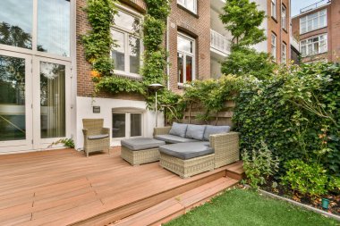 Yeşillik ve modern tasarım unsurları ile çevrili rahat koltukların bulunduğu şık bir açık hava alanı rahatlamayı ve estetiği artırır..