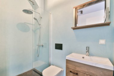 Zarif bir duşun, minimalist bir dolabın ve rahatlatıcı bir renk paletinin olduğu şık, modern bir banyo rahatlama ve hijyen için sakin bir atmosfer yaratıyor..