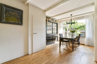 Ahşap zemin, zarif bir avize ve modern ve klasik mobilyaların karışımından oluşan şık bir yemek odası, sıcak bir atmosfer yaratıyor..