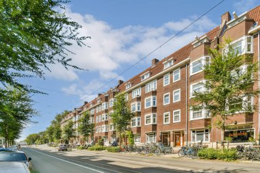 Büyüleyici tuğla binalar, yemyeşil ağaçlar ve sakin bir şehir ortamı yaratan huzurlu bir yol içeren pitoresk bir sokak manzarası..