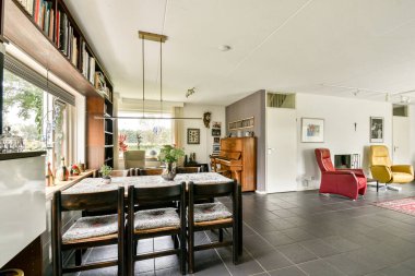 İçinde büyük bir piyano, canlı mobilyalar ve zarif bir dekorun bulunduğu şık bir modern oturma odası. Doğal ışık davetkar atmosferi güçlendirir.