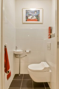 Bu çağdaş banyo düz çizgiler, temiz estetik, sergilenen beyaz fayanslar, minimal armatürler ve şık bir dokunuş için sanatsal duvar dekorasyonu içerir..