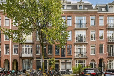Amsterdam 'ın pitoresk caddesinde güzel tarihi mimari, bereketli yeşillik ve şehrin cazibesini yakalayan park edilmiş bisikletler sergileniyor..