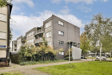 Yeşillik ve yürüyüş yollarıyla çevrili çağdaş apartman manzarası kentsel yaşam tarzını gösteriyor. Mimari doğayla güzel bir şekilde harmanlanır..