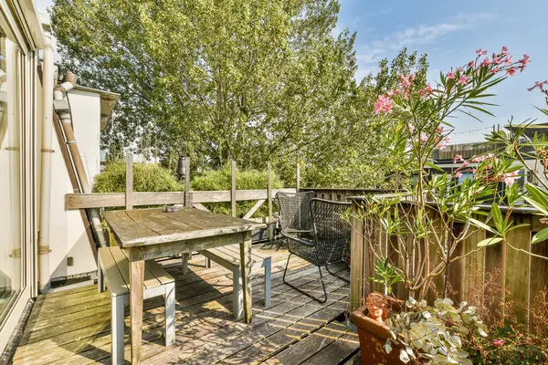 Bereketli yeşillik ve canlı çiçeklerle çevrili ahşap mobilyalarla dolu sakin bir bahçe, rahatlama ve toplanma için mükemmel..