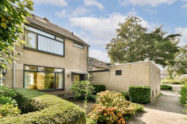 Canlı yeşillik ve bakımlı bahçelerle çevrili, huzurlu bir banliyö manzarası olan modern bir ev manzarası..