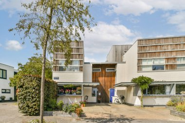 Temiz çizgiler ve geniş pencerelerle çevrili, doğa ve modernliğin bir karışımını yansıtan, iyi korunmuş yeşillik ve çiçeklerle çevrili çağdaş bir mimari tasarım..