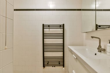 Şık bir havlu asacağı ve modern lavabonun olduğu gösterişli bir banyo. Beyaz fayanslar, çağdaş tasarımı ön plana çıkaran temiz ve parlak bir ortam yaratıyor..
