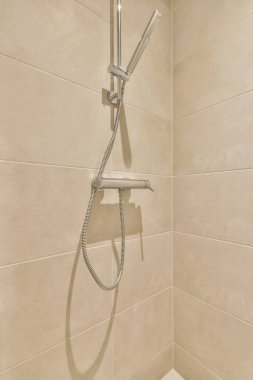 Duş başlığı ve duvarında bir cep telefonu olan beyaz fayanslı bir banyo.