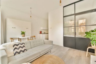 Doğal ışık ve yeşillikle tamamlanmış rahat bir kanepe, yemek alanı ve mutfağı olan şık ve modern bir minimalist oturma odası..