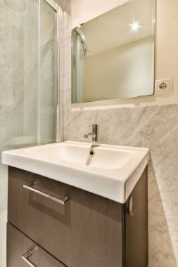 Şık ve çağdaş bir banyo, cam duş, zarif eşyalar ve şık bir dolap. Modern ev estetiği için mükemmel..