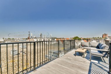 Şehrin gökyüzü ve şehir çatılarıyla çevrili, panoramik manzaralı, rahat bir oturma yeri olan şık bir teras..