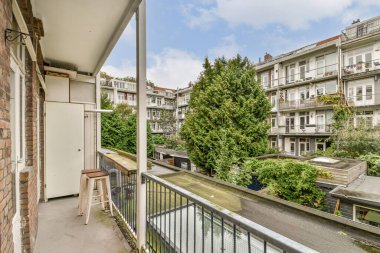 Huzurlu bir balkon manzarası, bereketli ağaçları ve şehir mimarisini sergiliyor, doğayı kentle harmanlıyor ve huzurlu bir ortamda yaşıyor..